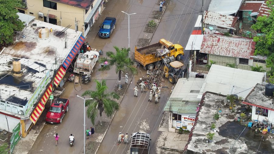 Vista aérea de una calle anegada con maquinaria y personal retirando escombro