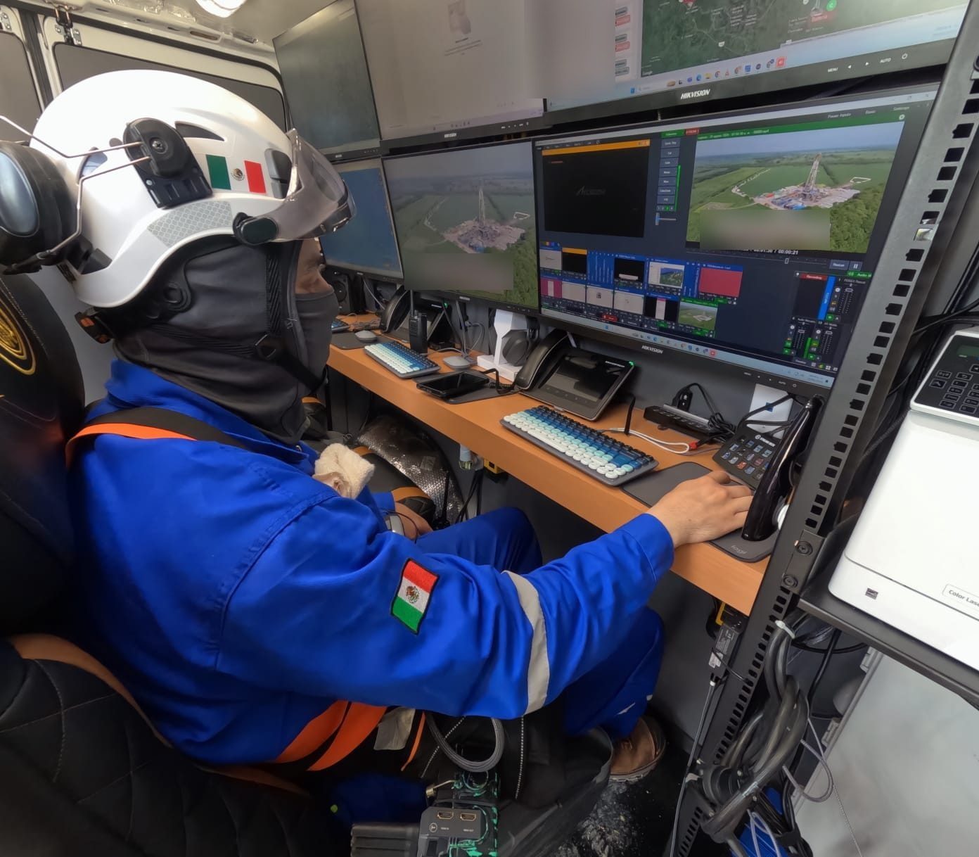 Operador de ICES en la consola de la unidad móvil, transmitiendo en vivo dos vistas aéreas de un equipo de perforación