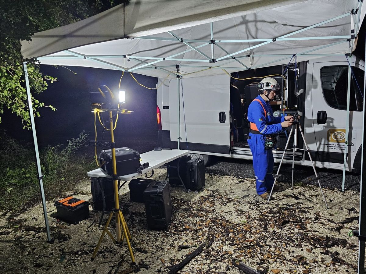 Unidad móvil operando de noche con iluminación propia y equipo en mesas de trabajo